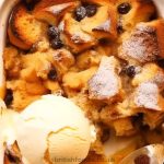 apricot sultanas bread and butter pudding in a baking pen topped with a scoop of vanilla ice cream