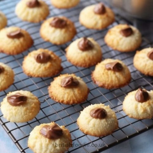 Mary Berry Coconut Biscuits on a wire rack with a drop of chocolate on top